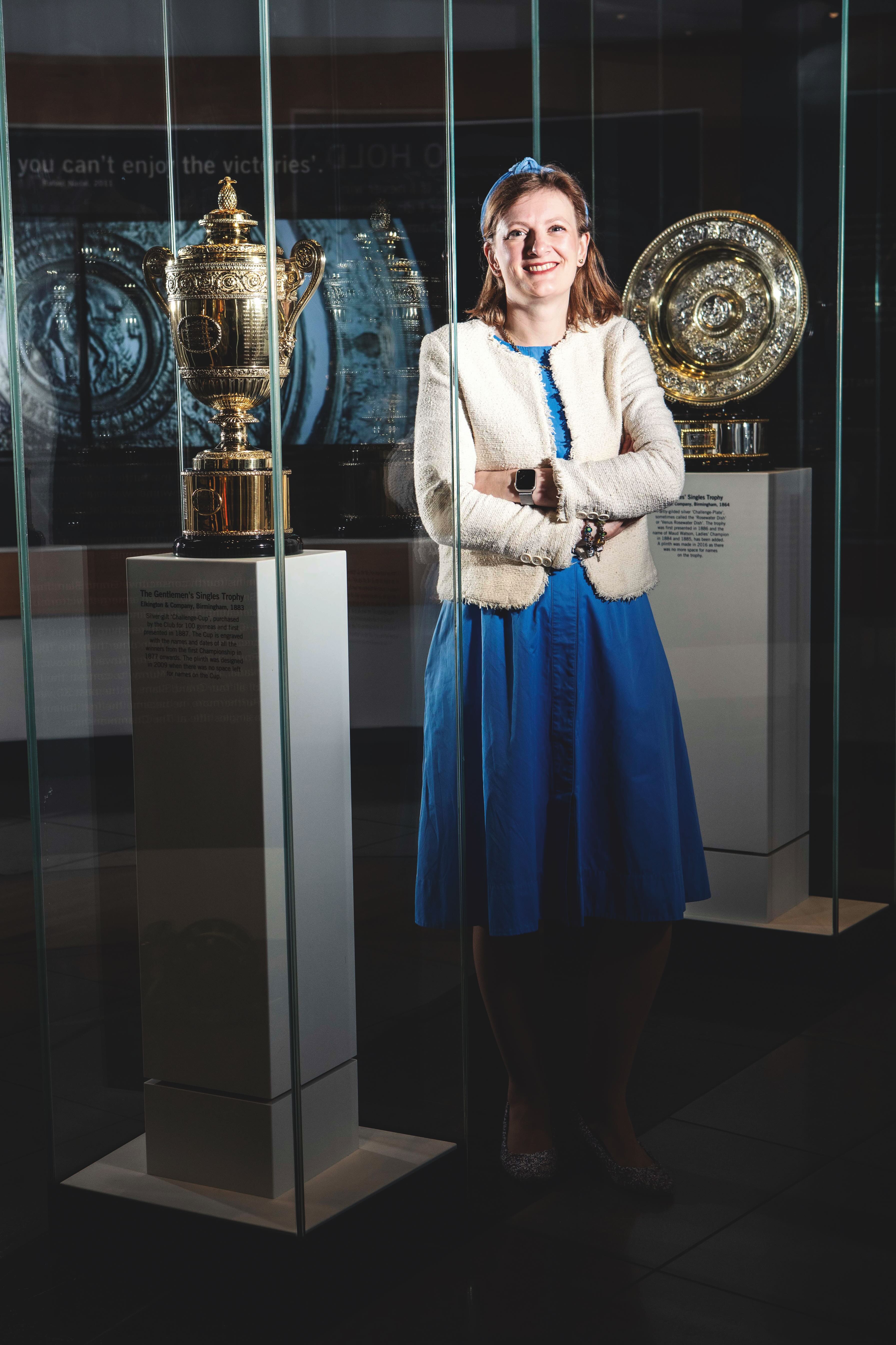 Emma Traherne, Museum Curator with Mens and Women&amp;rsquo;s trophies. With Archive of Tennis Rackets and 50th years of wheelchair tennis with medal.