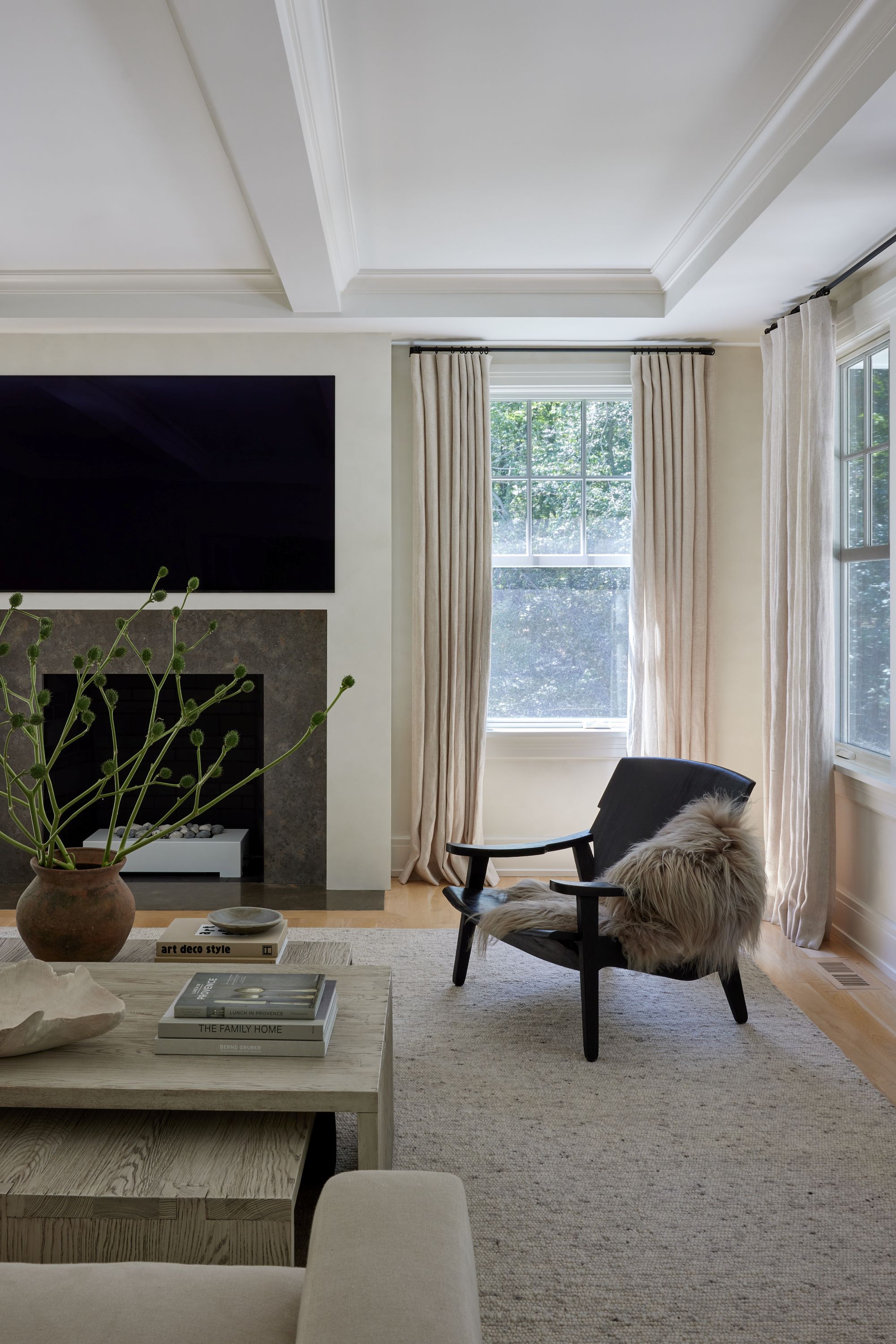 a living room with a black accent chair and a faux fur throw draped across its arm