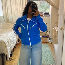 A woman wearing a blue jacket, blue jeans, and black tabi flats