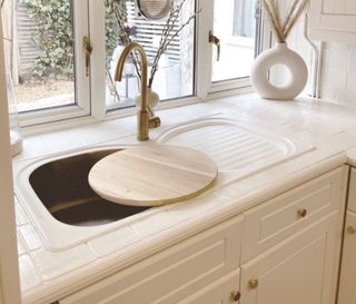 Becky Lane's new white kitchen sink, with a gold tap and a white vase