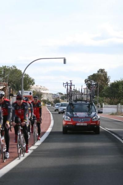 A team car offers some protection for the riders in urban areas