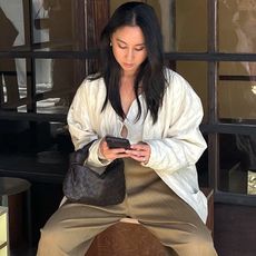 style influencer Jordan Risa wearing a white keyhole tie-front top, a woven brown bag, and pliss&eacute; tan pants