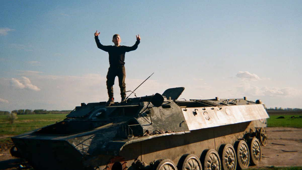 Bohdan, 13, stands on top of a burned out tank in Ukraine