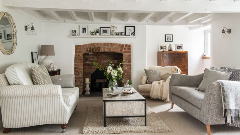 White living room in charming Devon cottage with brick fireplace and painted beams