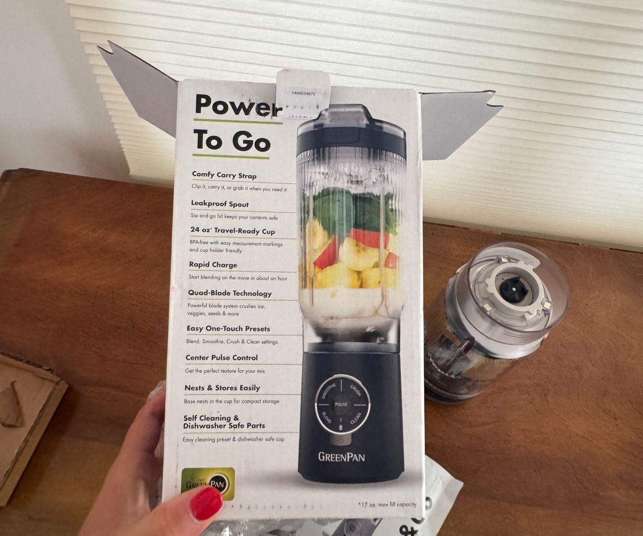 The white box for the GreenPan Spin &amp; Go portable blender being held up over a wooden table.