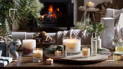 a living room console table with a fire in the background with a display of the best-selling The White Company home scents from Winter fragranced candles and diffusers