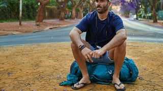 Backpacker sitting on his bag in the middle of a street 