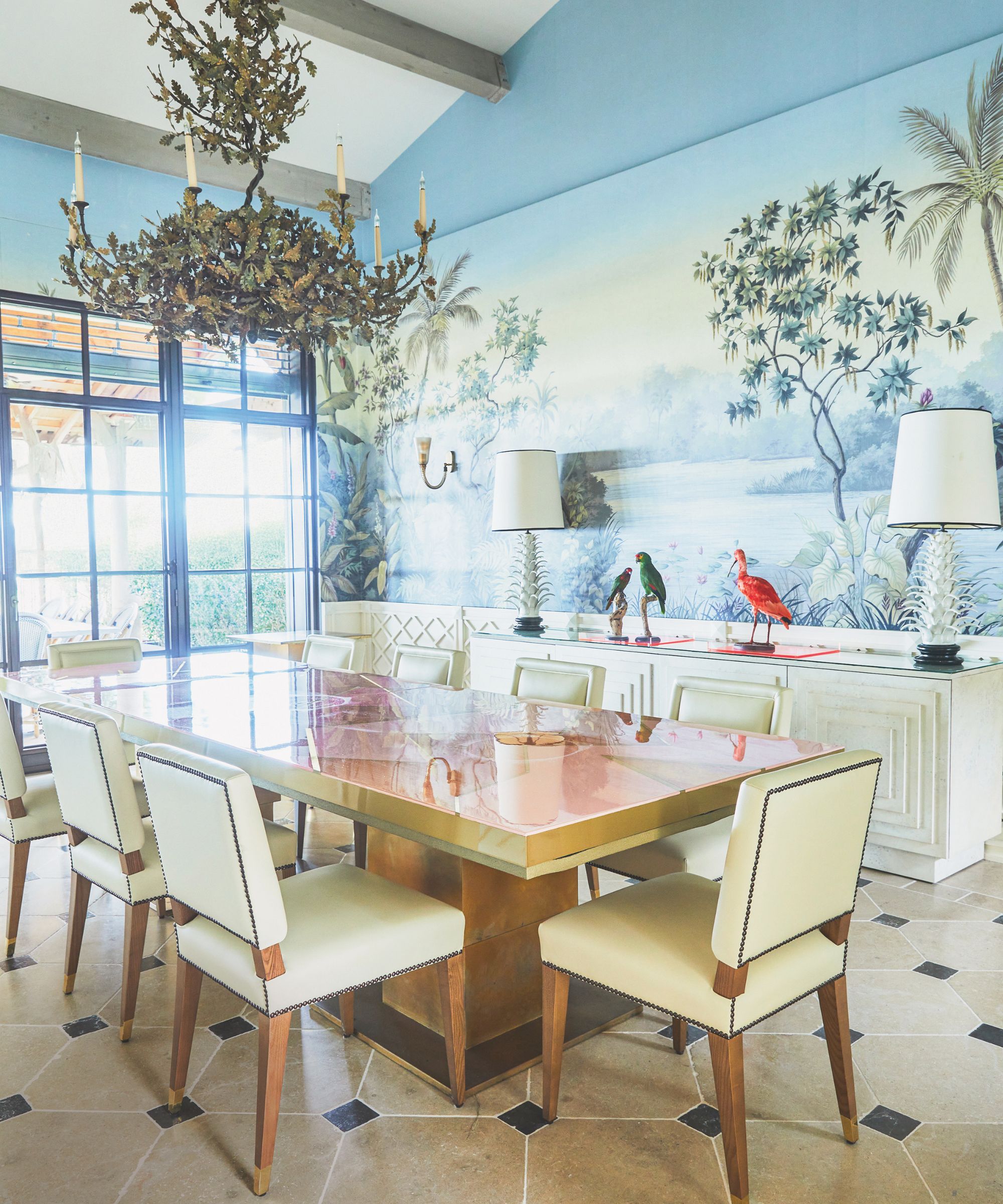 Dining room with a glossy table, cream leather chairs, and a tropical scenic mural on the wall