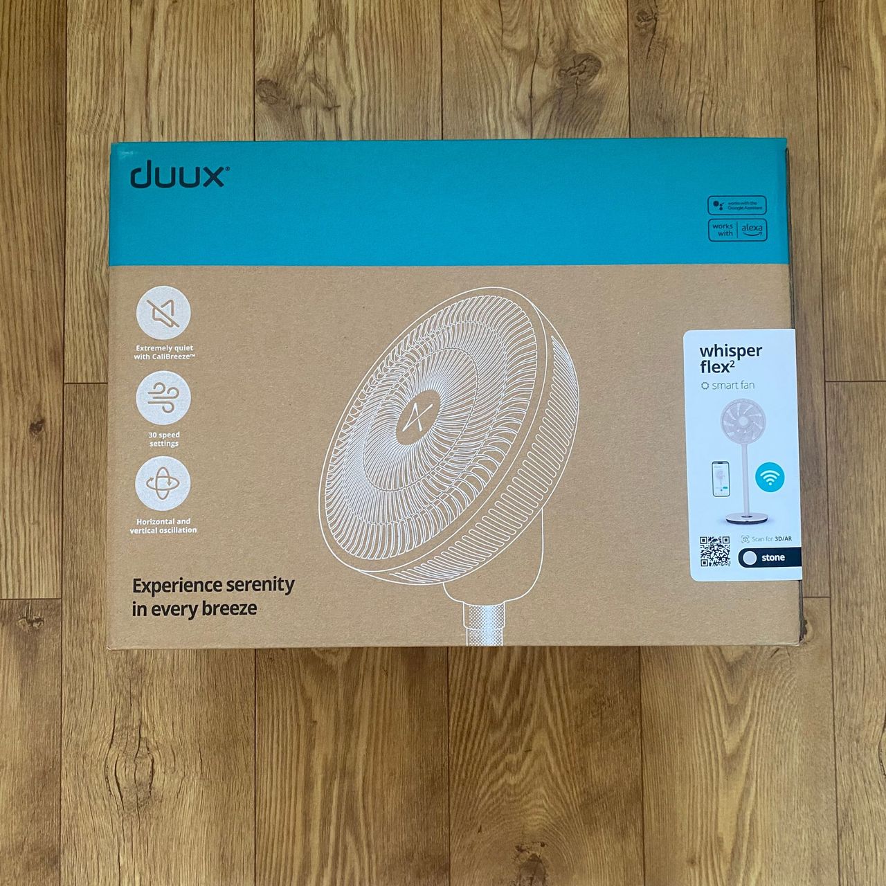Outer packaging of the Duux Whisper Flex 2 on a wood-look floor