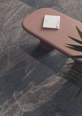 A stone floor and a pink side table