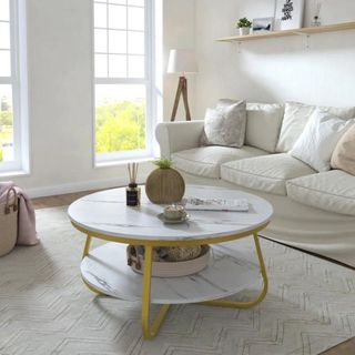 Mercer41 Celin white marble coffee table with gold accents, placed inside a white living room