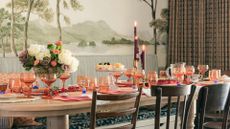 A dinner table set with flowers, candles, glassware and table mats