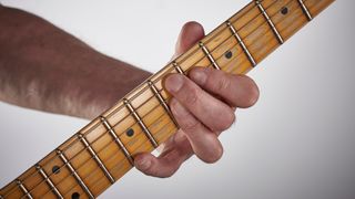 Man's hand playing an extended guitar chord