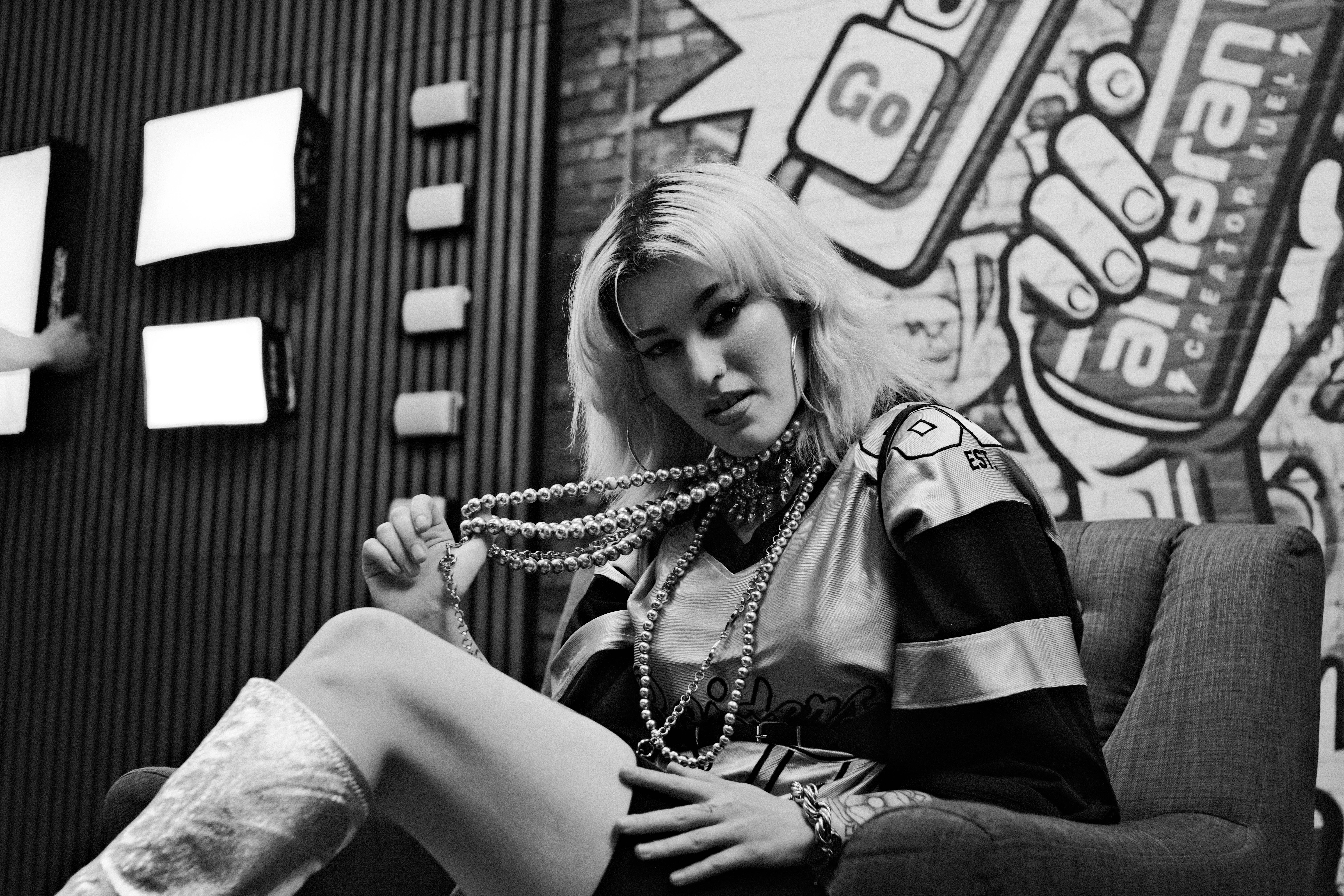 Portrait of a woman seated indoors wearing layered bead necklaces