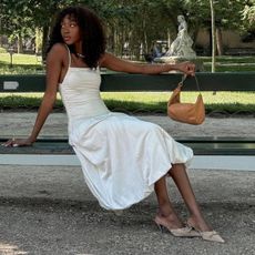 @emmanuellek_ wears a white midi bubble-hem dress with light brown mules and a tan suede bag