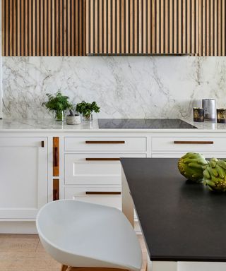 White kitchen with wood cabinets and marble backsplash