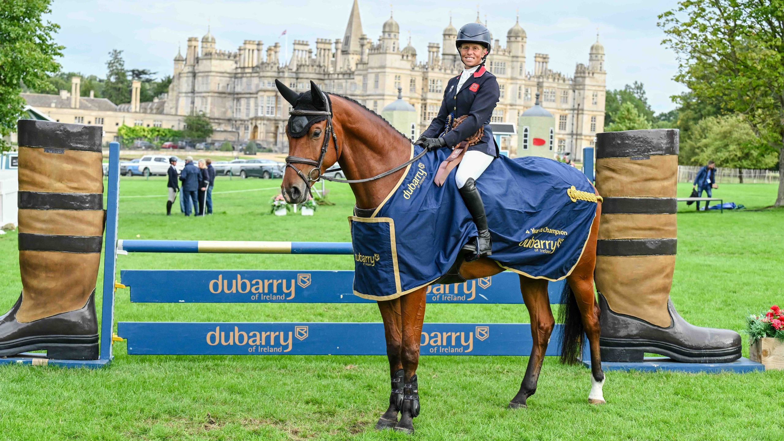 Ros Canter sits aboard winner of the four-year-old class at Burghley, Kilcorig Gotcha Talkin, who is standing in front of Burghley House in his Dubarry branded rug
