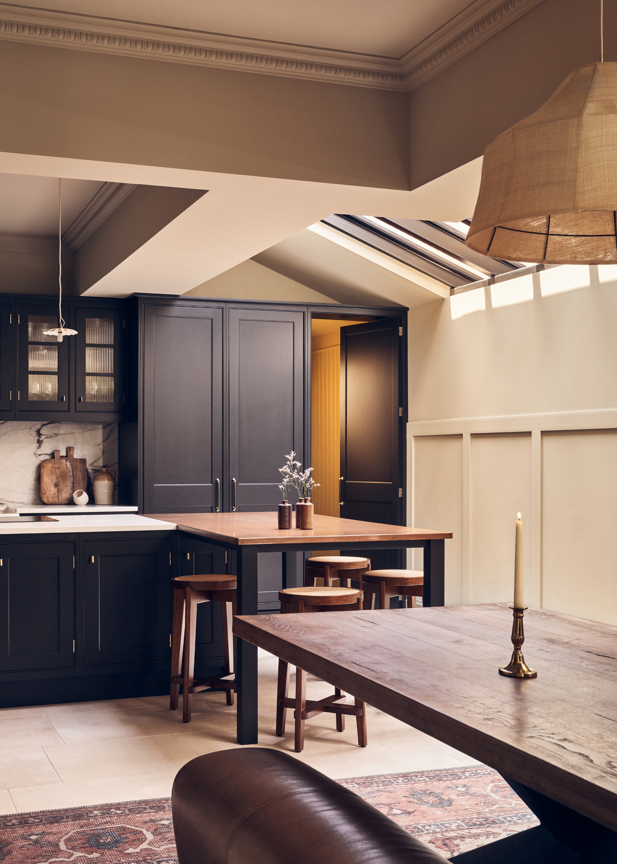 open plan kitchen with a split island and dark cabinet, leading into a dining area with dark wooden table and rug