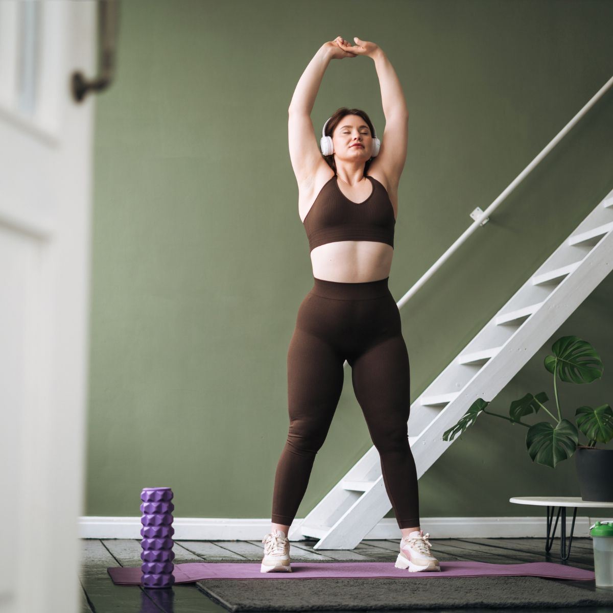 Cosy home workouts: A woman in brown gym kit, stretching at home after doing a sweat session