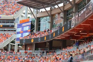 Clemson Tigers are ready to take the field and fans look on at a massive LED display in bright orange.
