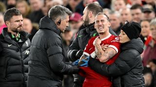 Kostas Tsimikas receives treatment from Liverpool's medical staff during the Reds' 1-1 draw with Arsenal in December 2023.