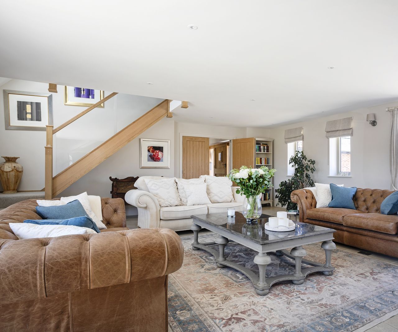 A large living room with three sofas and carpet and coffee table