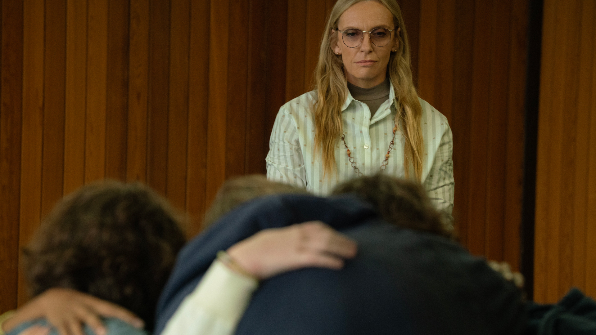 toni collette as evelyn overlooking a group of teens embracing each other in wayward