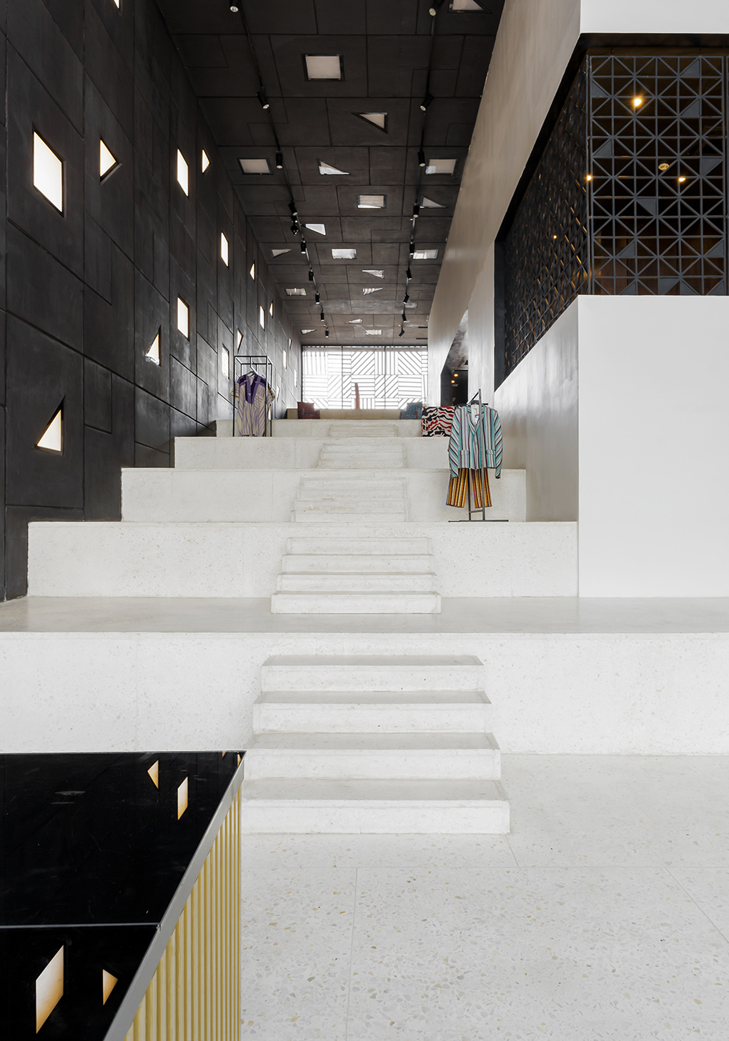 A strikingly designed concept stores features black tessellated walls letting the light through, a white-washed, terrazzo staircase, and colorful fashion buys.