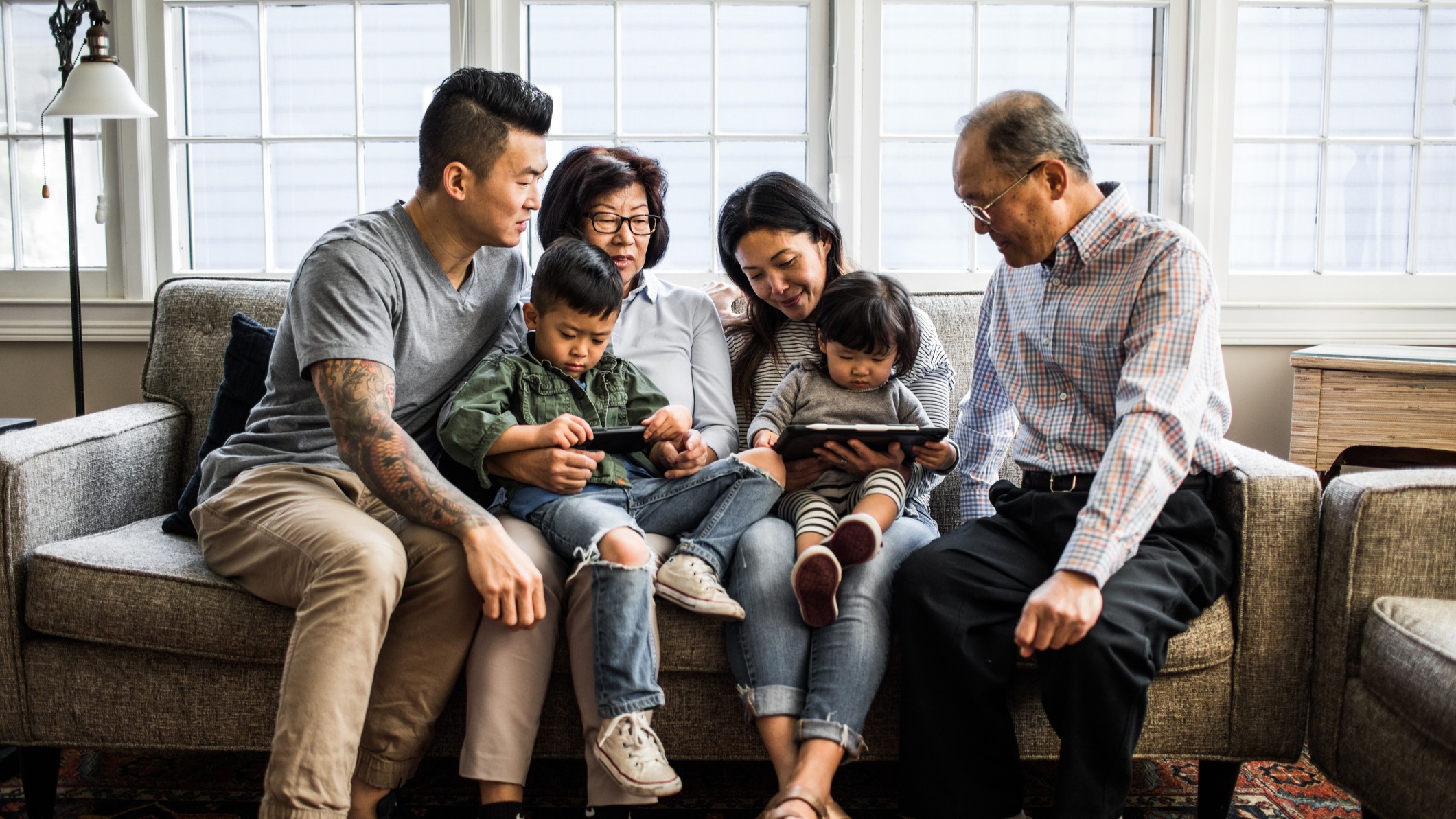 Three generations of a family sit together on a couch.
