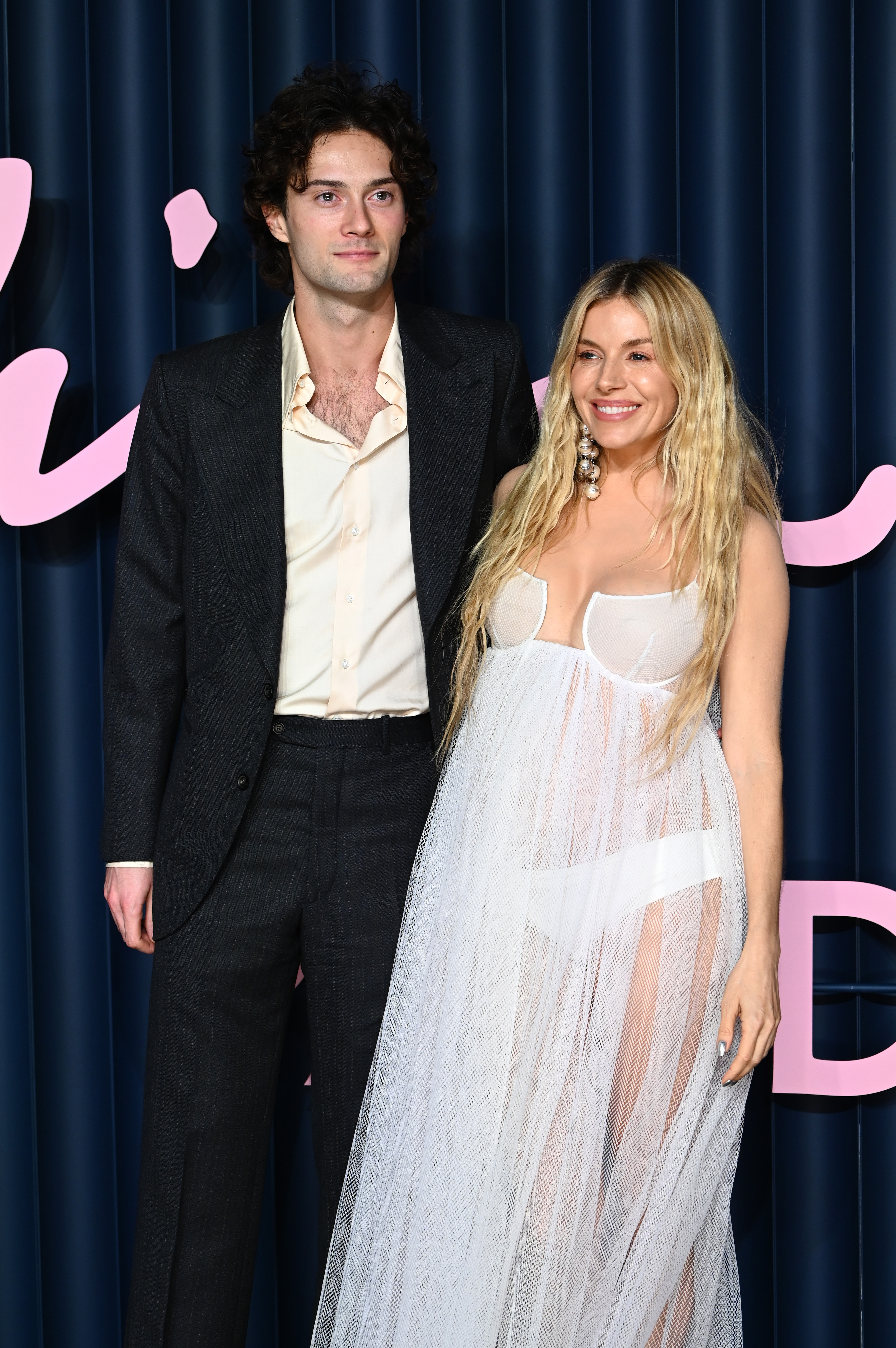 Sienna Miller and her boyfriend Oli Green pose on the red carpet at The Fashion Awards in London as she announces her pregnancy with a sheer white dress