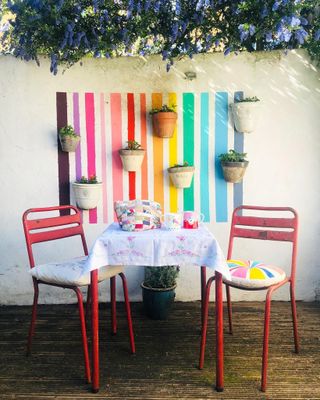 Multicolored garden wall with pots and a pink bistro set