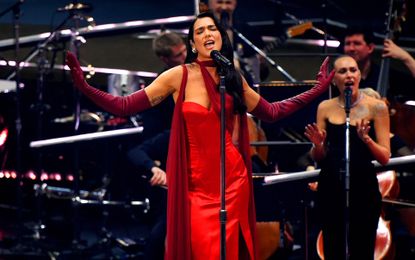 Dua Lipa with dark black hair performing at royal albert hall