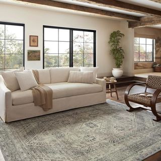 A farmhouse-style living room with a white sofa and a blue and white area rug