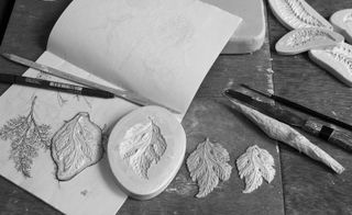 A photo of an artists book with sketches and a plaster molds of leaves