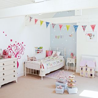 white kids bedroom with feature wall, wrought iron bed and bunting