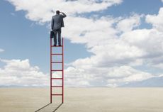 Businessman Standing On A Ladder Looking Into The Distance