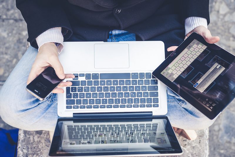 A man multitasks with various devices.