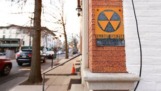 A photo of sign on a building that reads "fallout shelter"