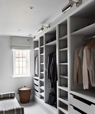 Gray walk in wardrobe with hanging rails, shelves and drawers