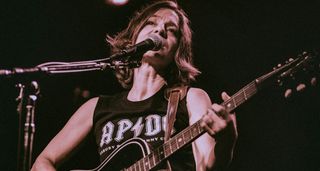 Ani DiFranco plays an acoustic guitar onstage