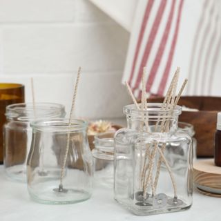 Glass jars with wicks on white kitchen table