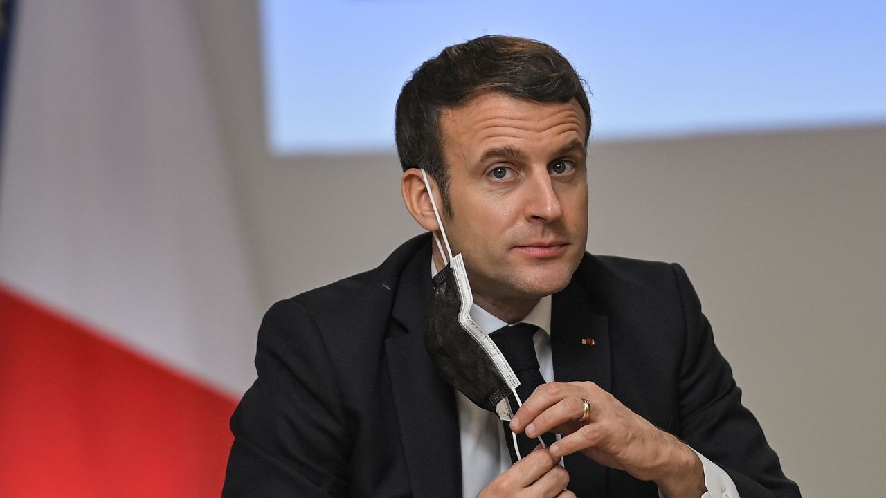 Emmanuel Macron removes a protective face mask to take a drink of water.