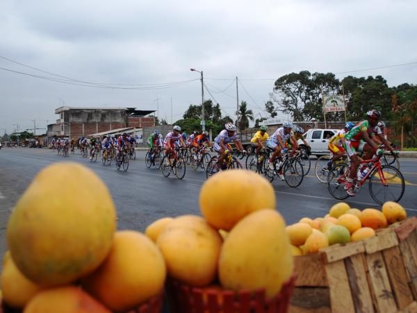 The peloton races past a Mango stall
