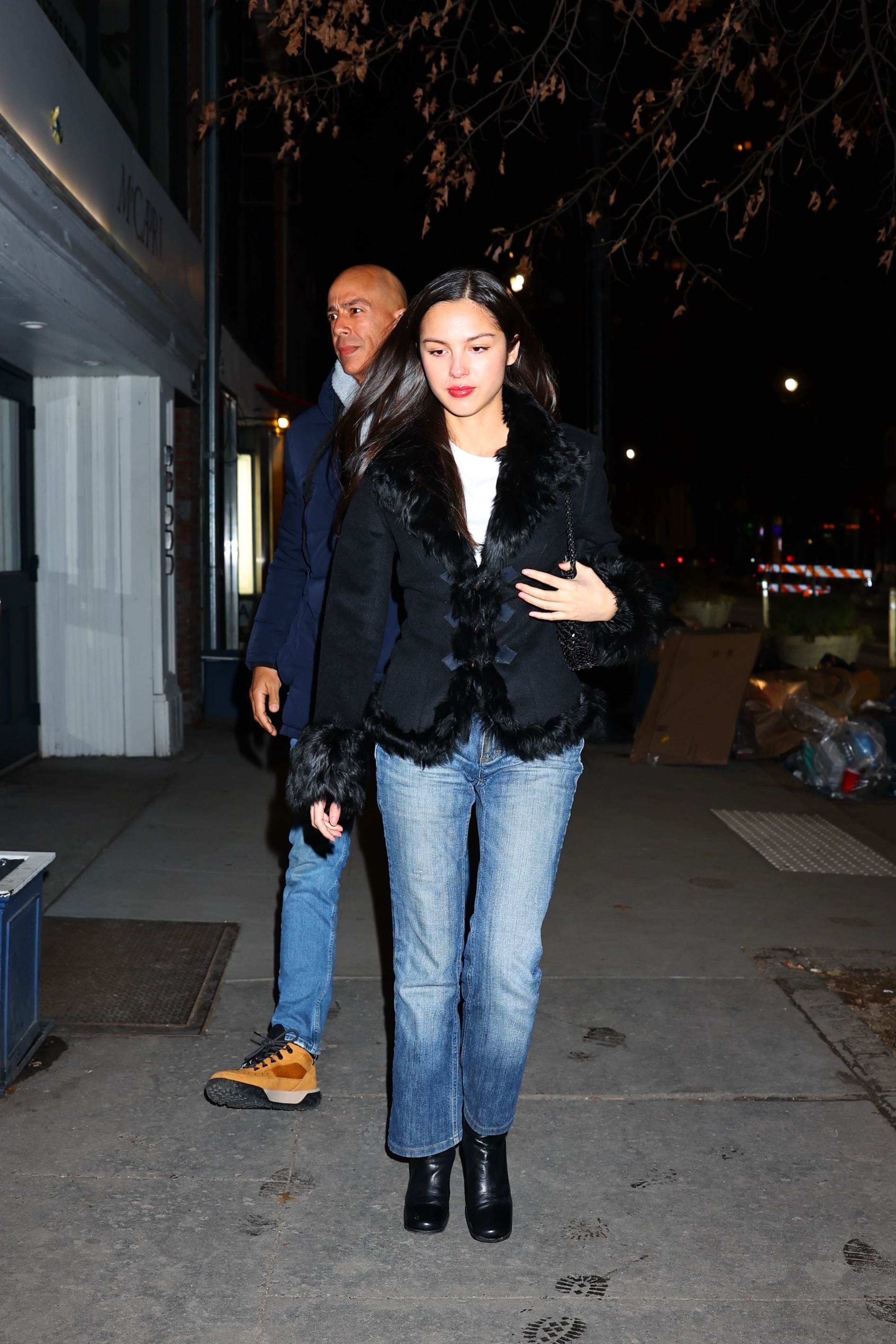 Olivia Rodrigo wears blue cigarette jeans with square-toe boots and a fur-trimmed jacket.