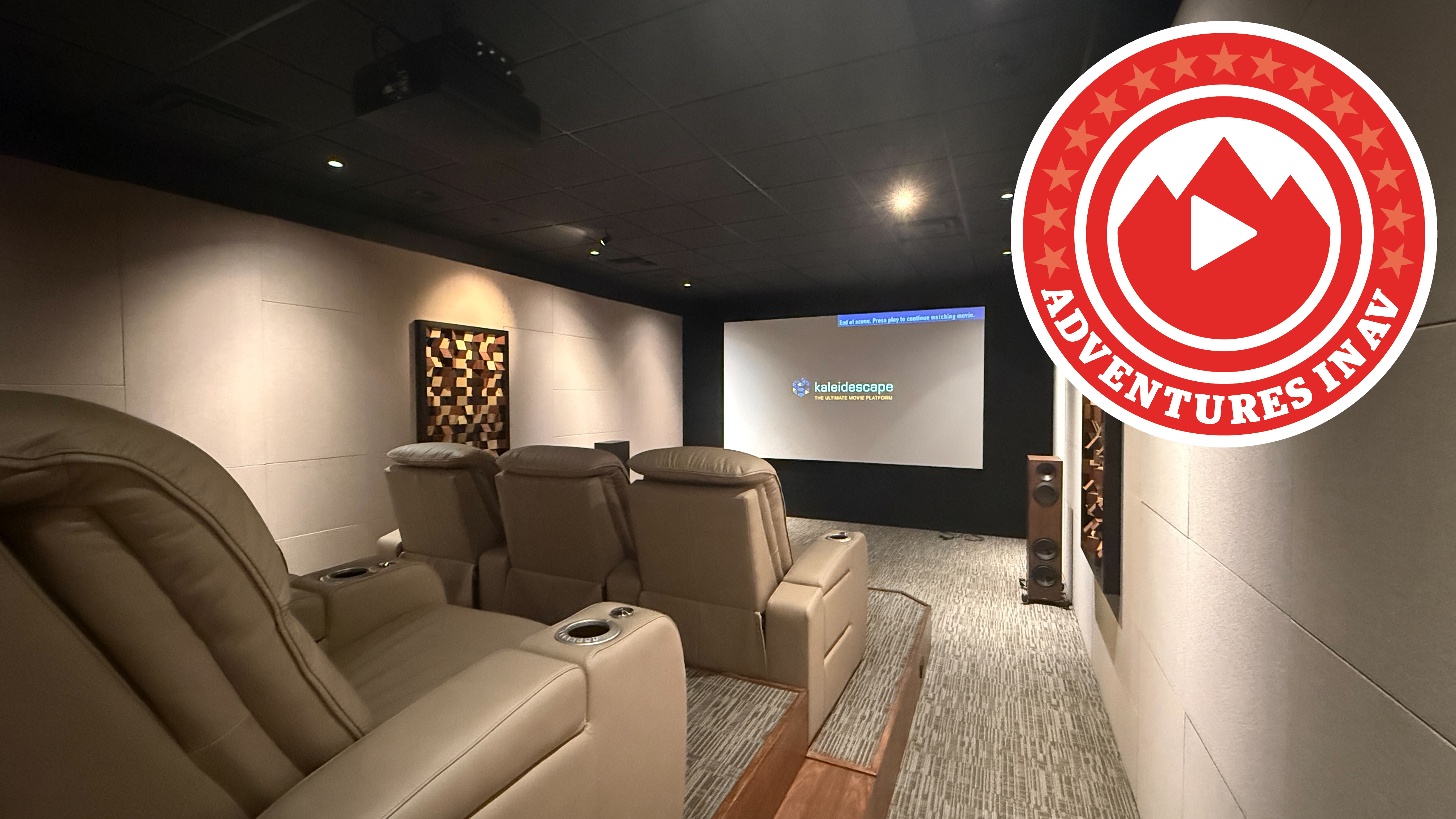 A home theatre reference room with leather recliners, a ceiling mounted projector, and a projector screen