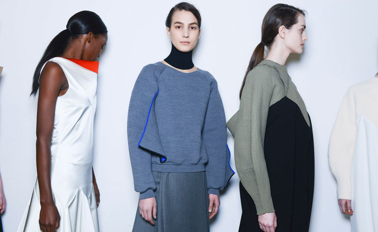 One woman in a white dress, one in a blue jumper and skirt, and one in a black and grey dress