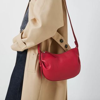 Model wearing red bag and camel trench coat