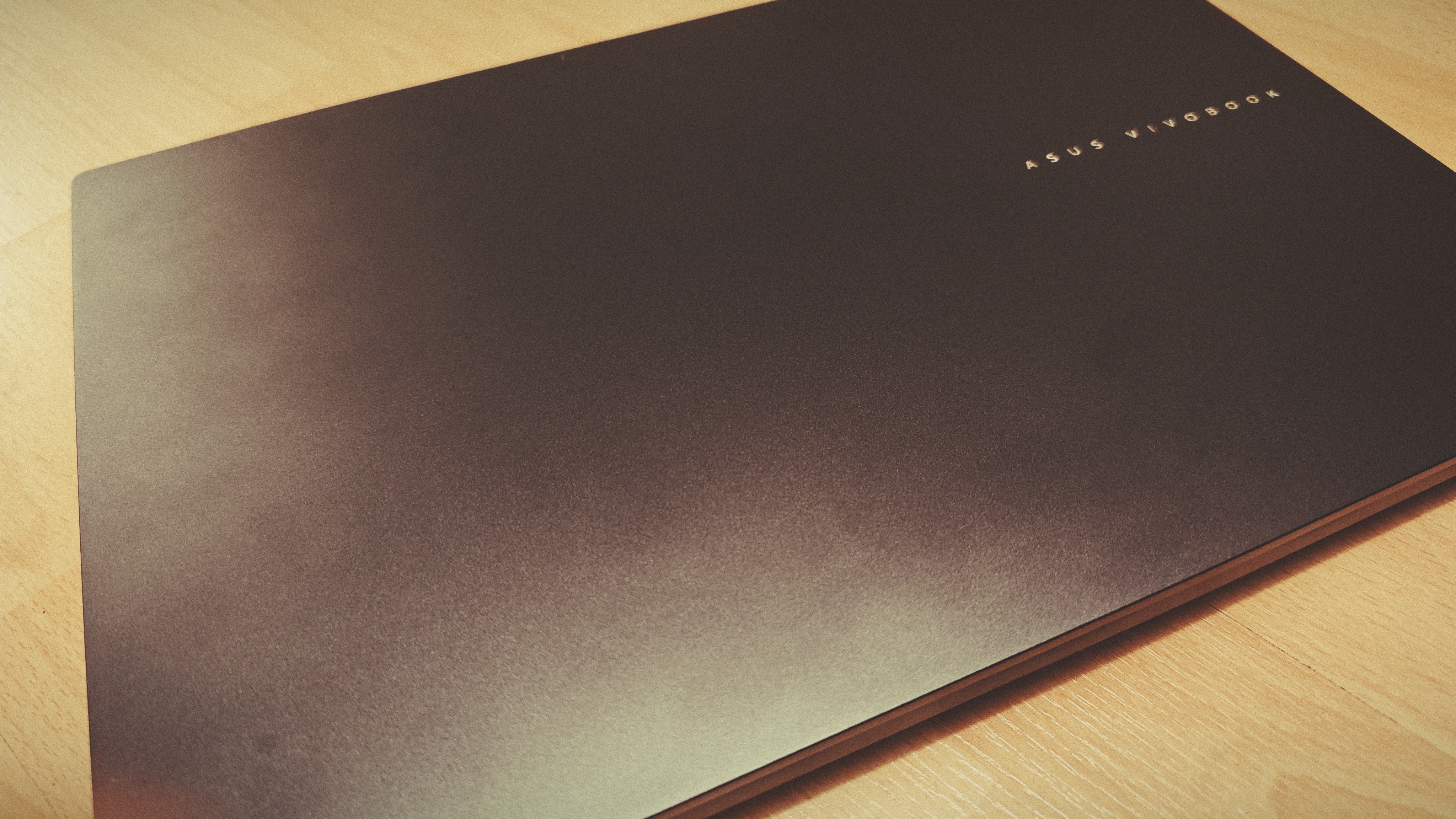 An Early Grey ASUS Vivobook Pro 15 OLED (2024) sitting on a wooden floor