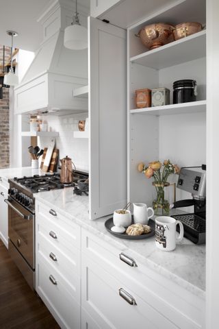 A cupboard containing a coffee maker in a white kitchen