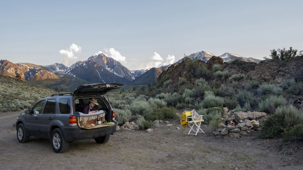 A person camping in their car in the mountains